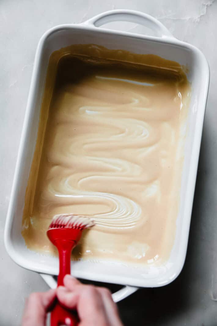 brushing tahini in the base of the baking dish