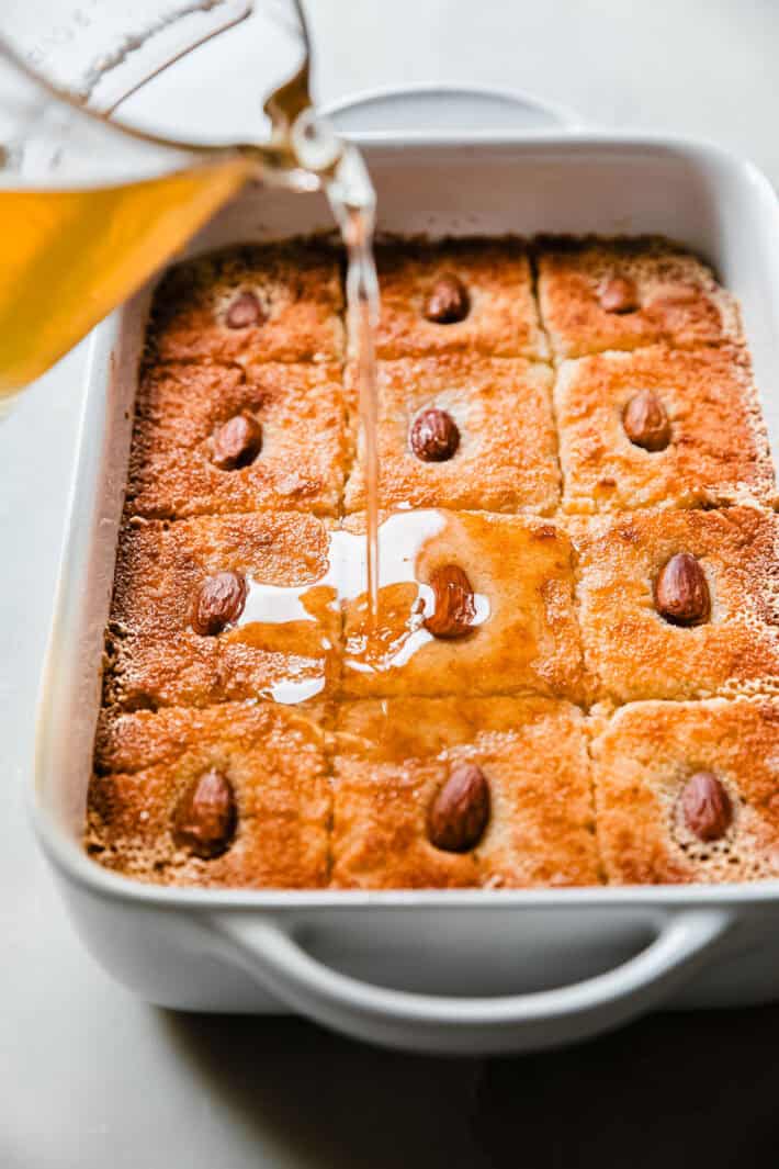 drizzling simple syrup over prepared cake