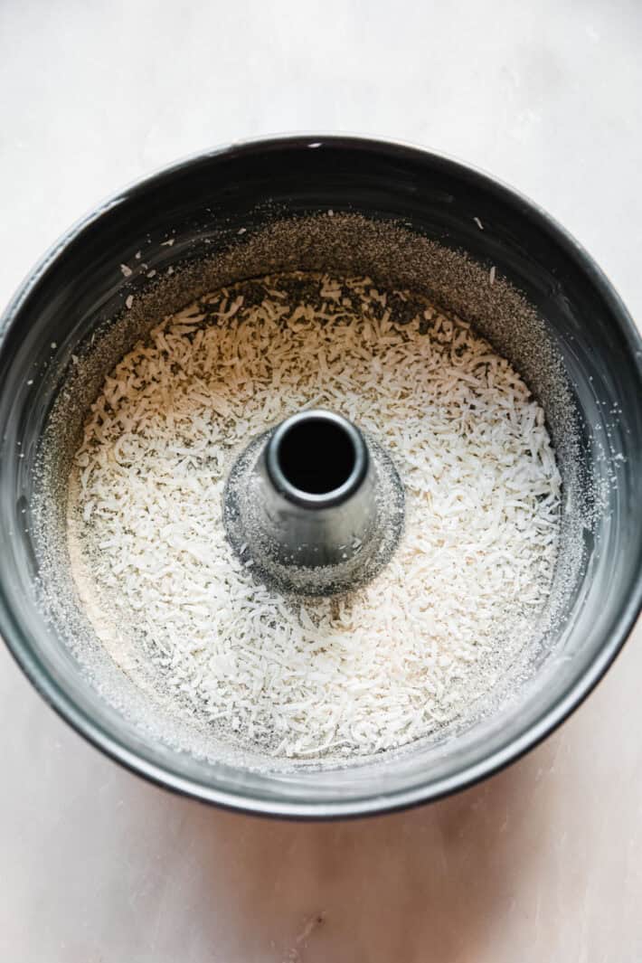 sugar and unsweetened coconut flakes in the bottom of an angel food cake pan