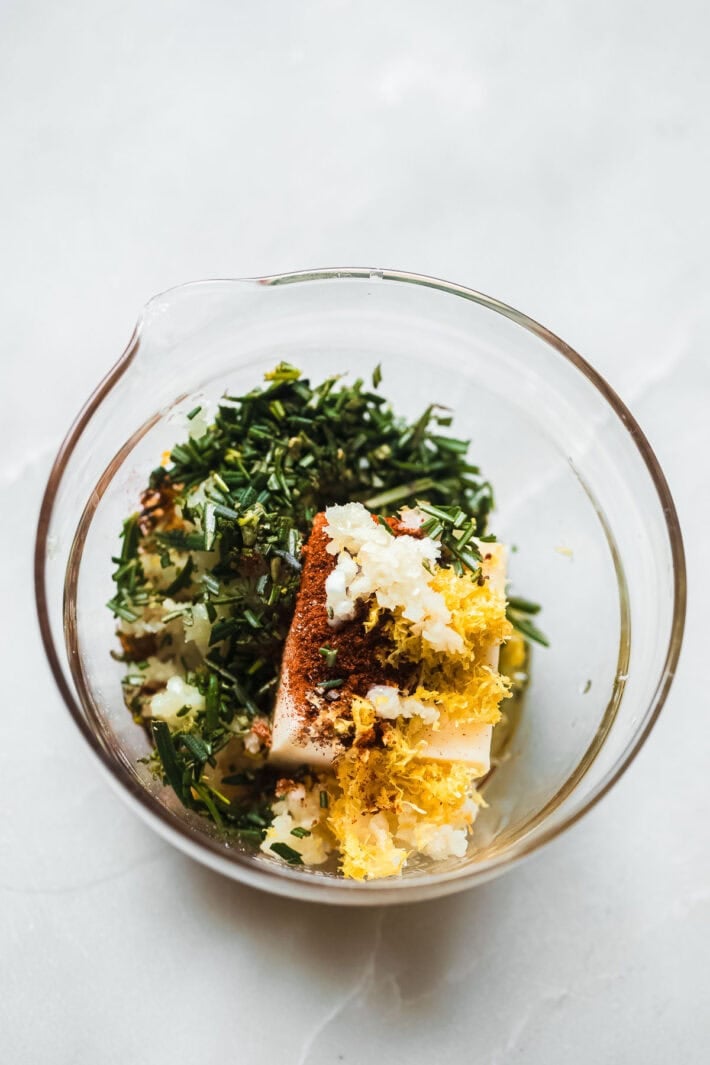 ingredients for rosemary butter in clear glass dish