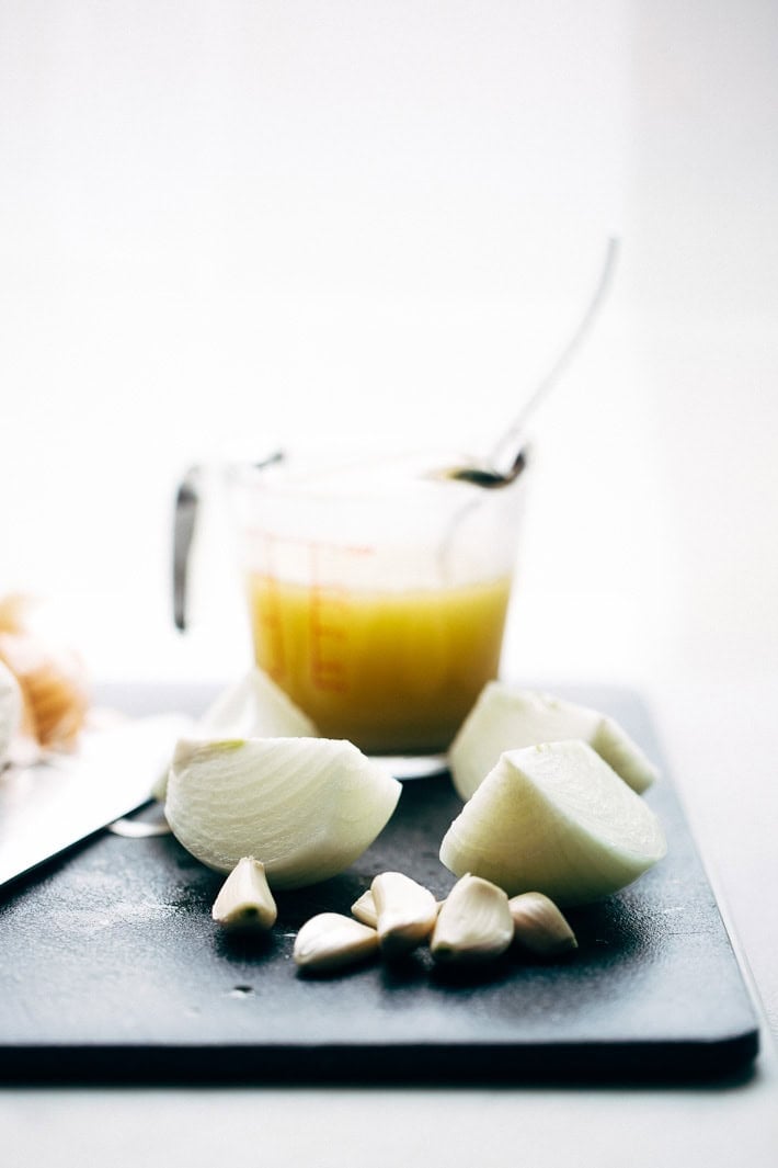onions, garlic and broth on cutting board