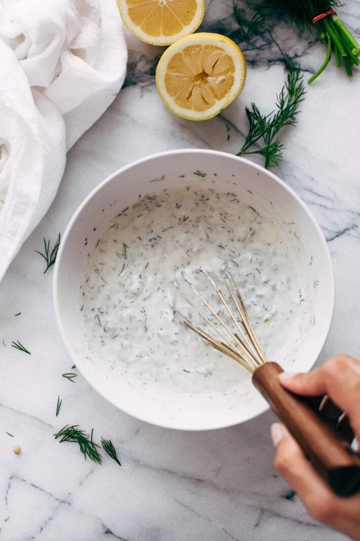 tzatziki in bowl with hand whisking