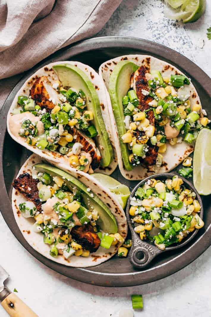 chicken tacos with corn and green onions with lime wedges