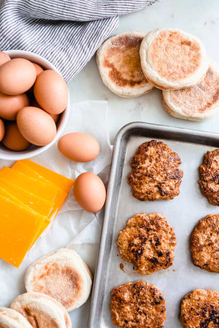 eggs, cheese, and English muffins with sausage patties before assembling