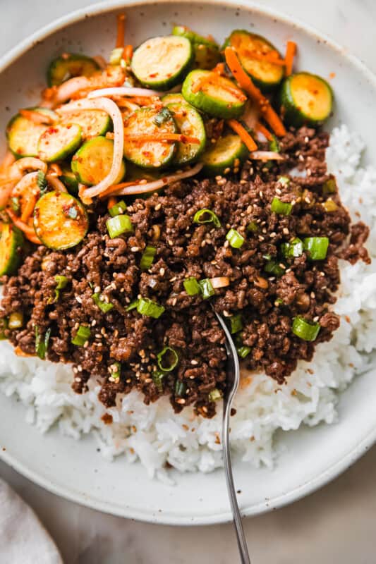 gochujang beef in bowl with fork and cucumber salad