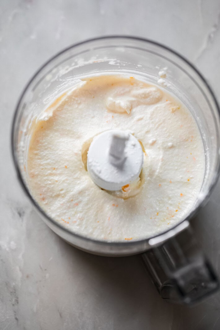 whipped ricotta in food processor bowl with orange zest speckles