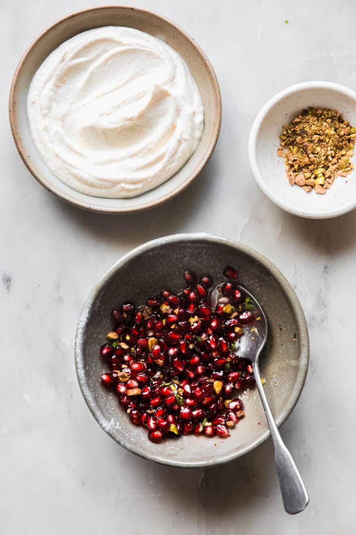 prepped dip with pistachios in bowl and pomegranate topping
