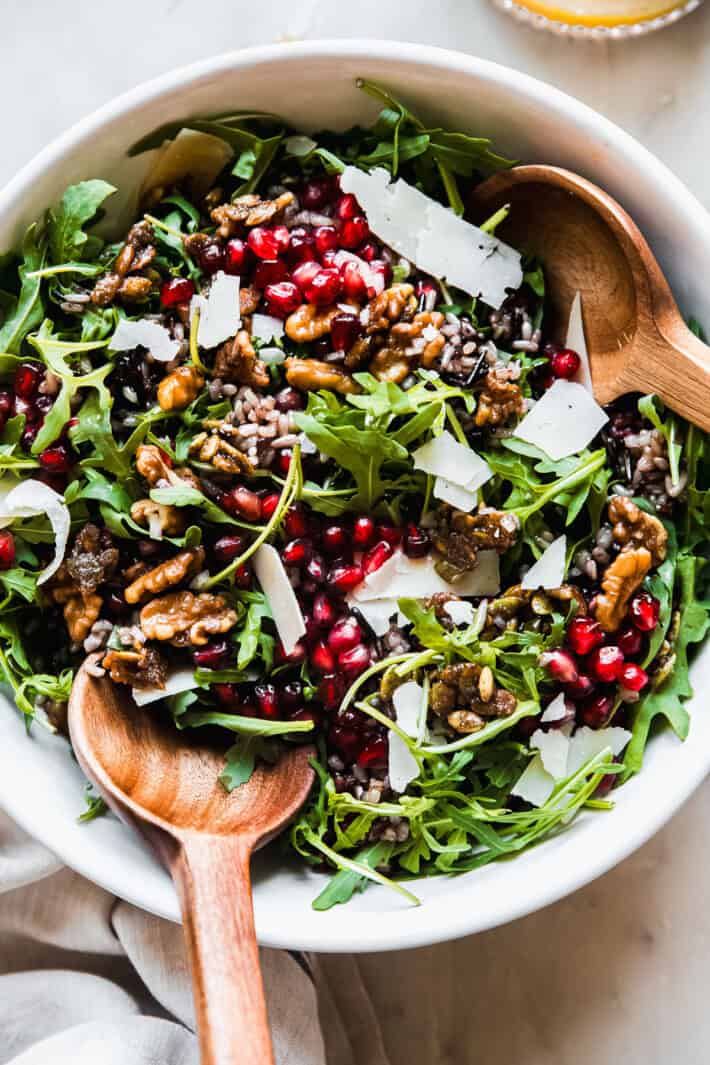 holiday salad in white bowl with serving spoons