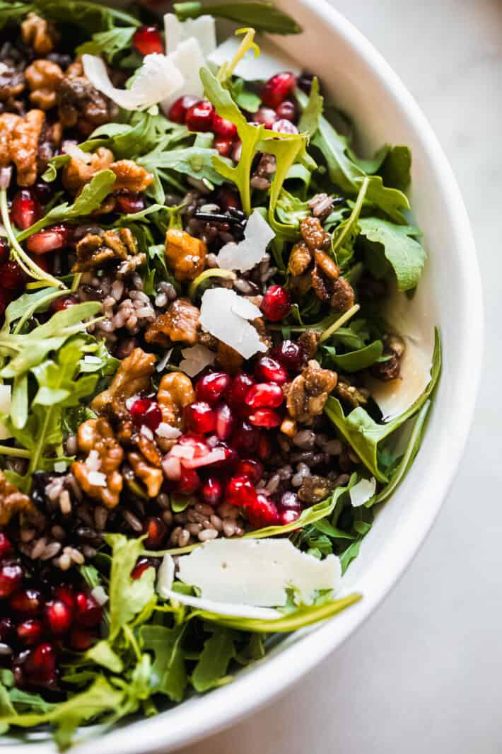 close up of salad showing pomegranate, wild rice, arugula, and more