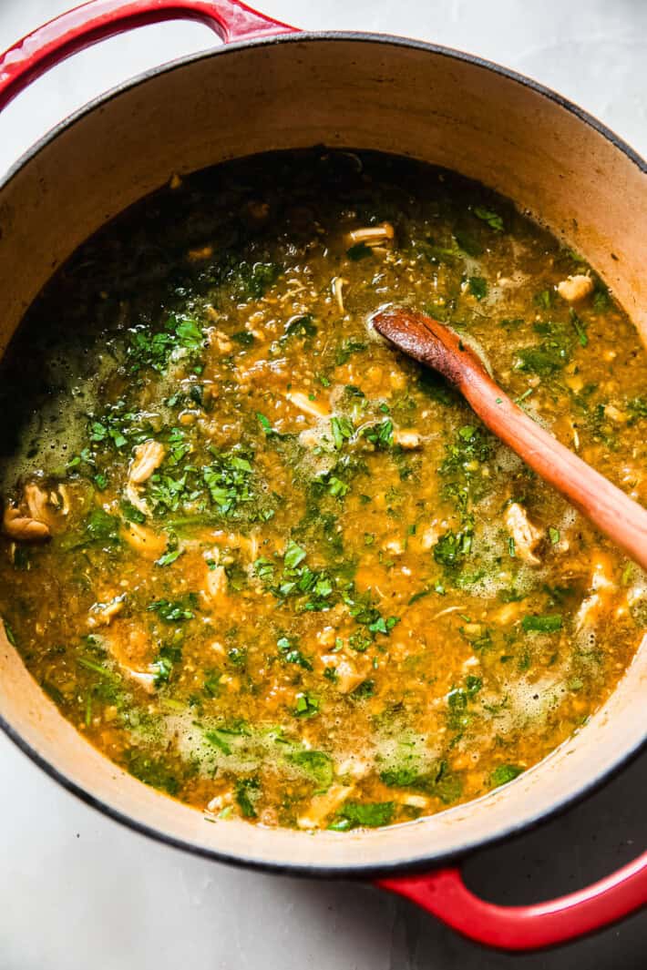 red lentil soup topped with fresh parsley in cast iron pot