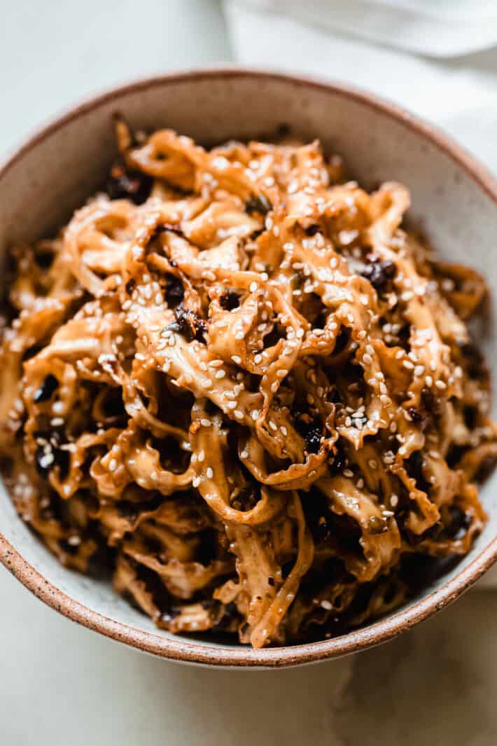 scallion soy noodles in bowl topped with sesame seeds