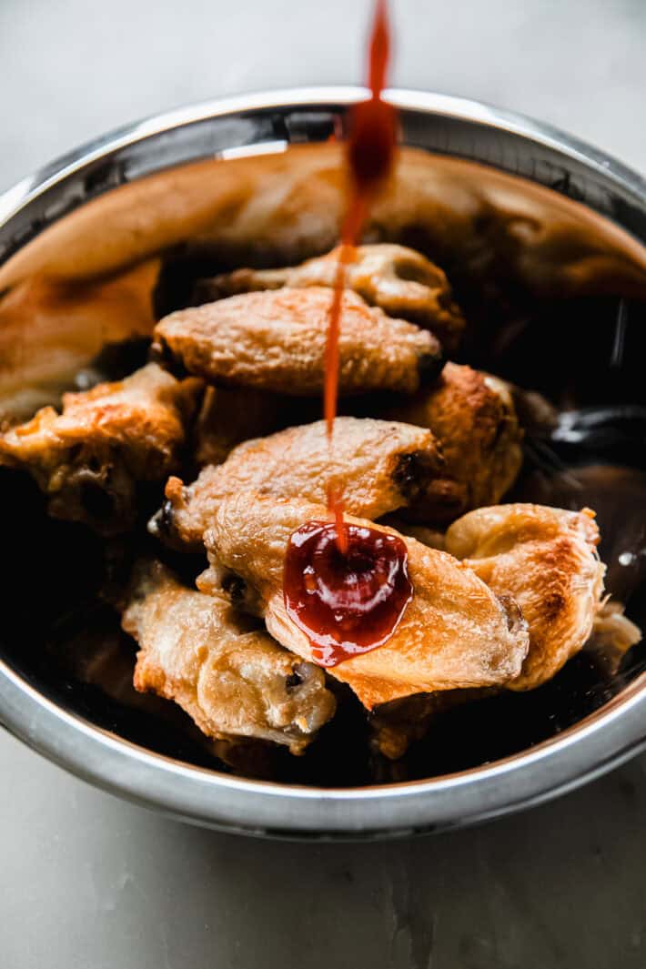Drizzling sauce over wings