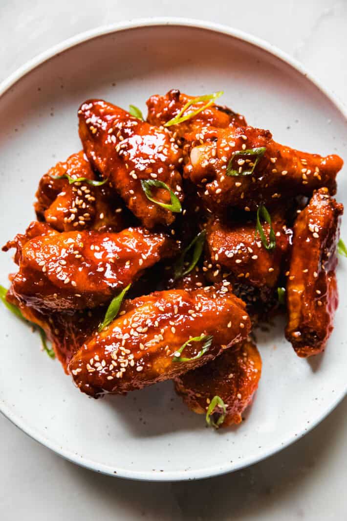 garlic gochujang wings on plate with green onions and sesame seeds