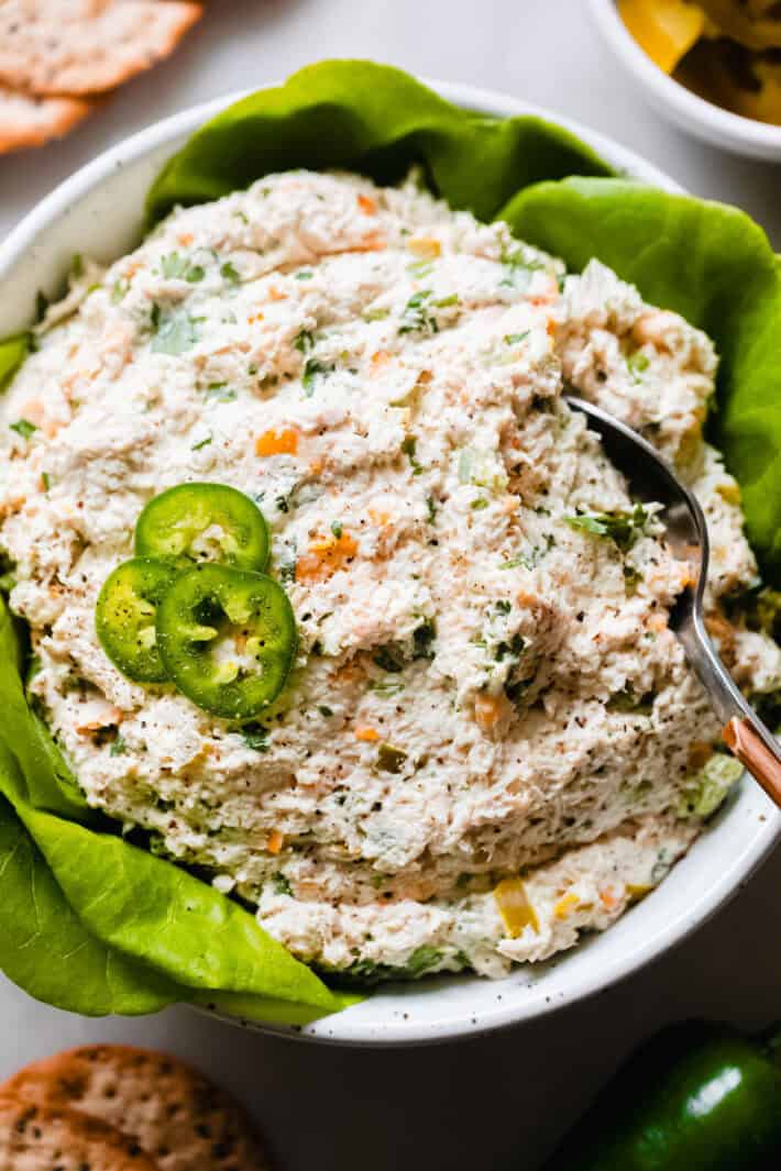 chicken salad topped with jalapeños in a bowl with a spoon