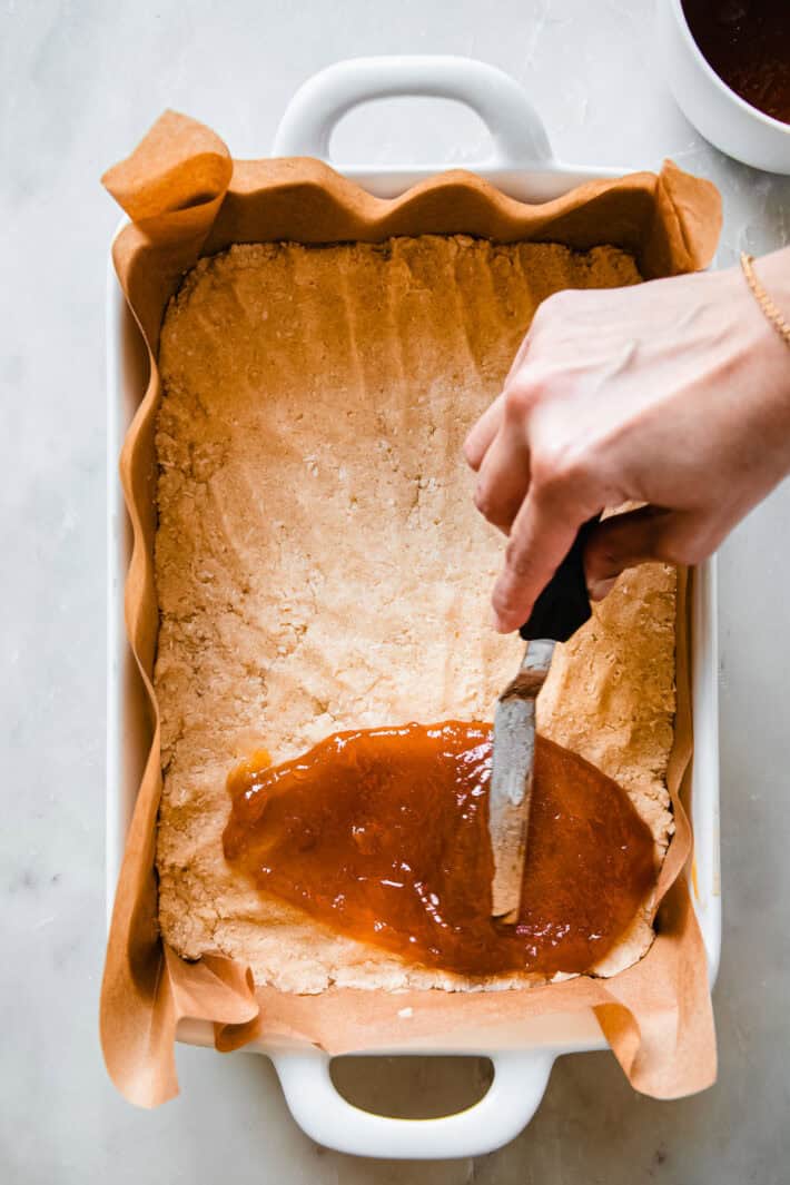 apricot preserves spread over crumble layer