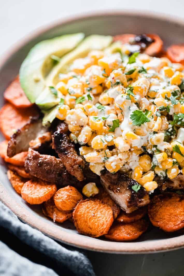 sweet potatoes with chicken thighs and street corn salad on top
