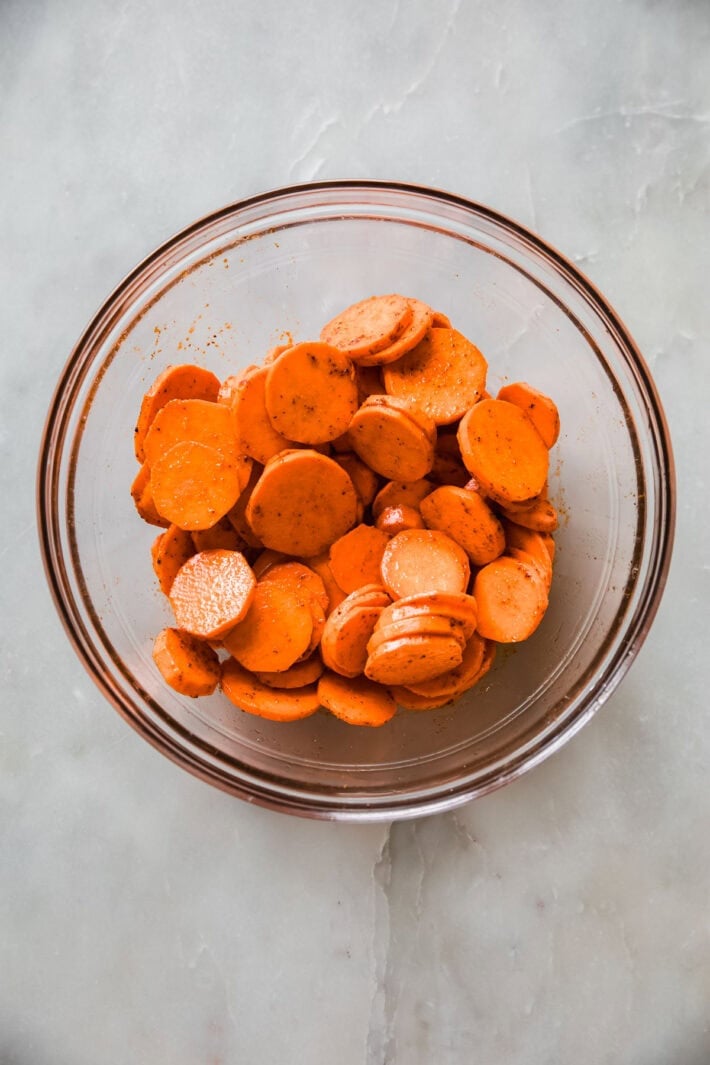 seasoned sweet potatoes in bowl before cooking