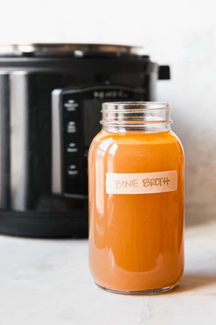 mason jar with bone broth in front of pressure cooker