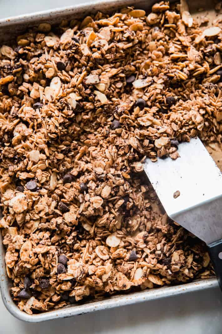 chocolate chip cookie granola on baking sheet with spatula