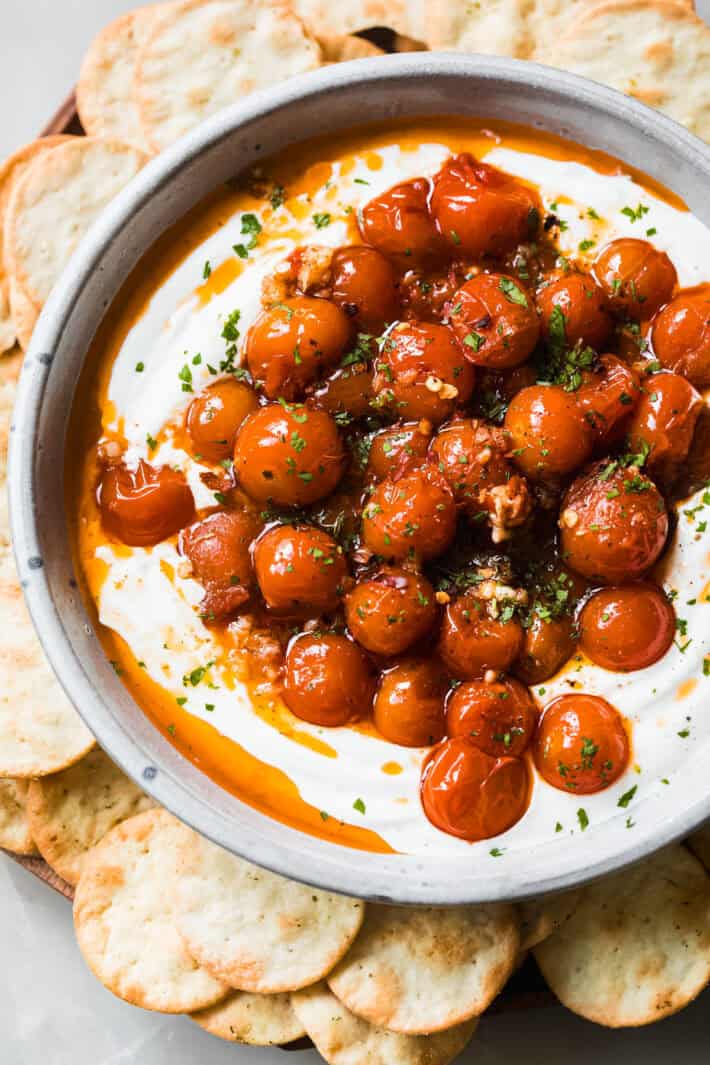 roasted tomato labneh dip in bowl surrounded by crackers