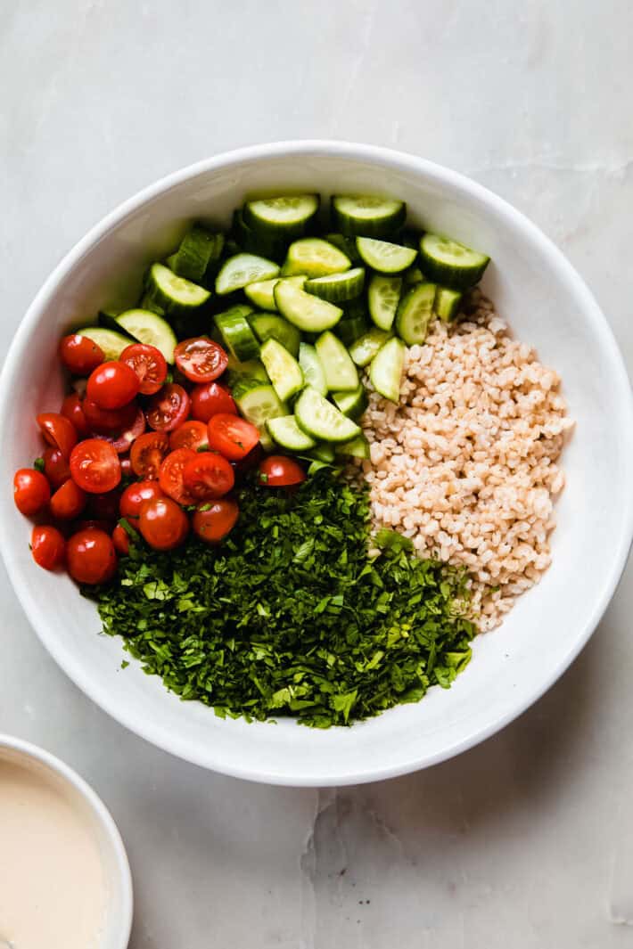 cucumbers, tomatoes, short grain brown rice, and herbs in bowl
