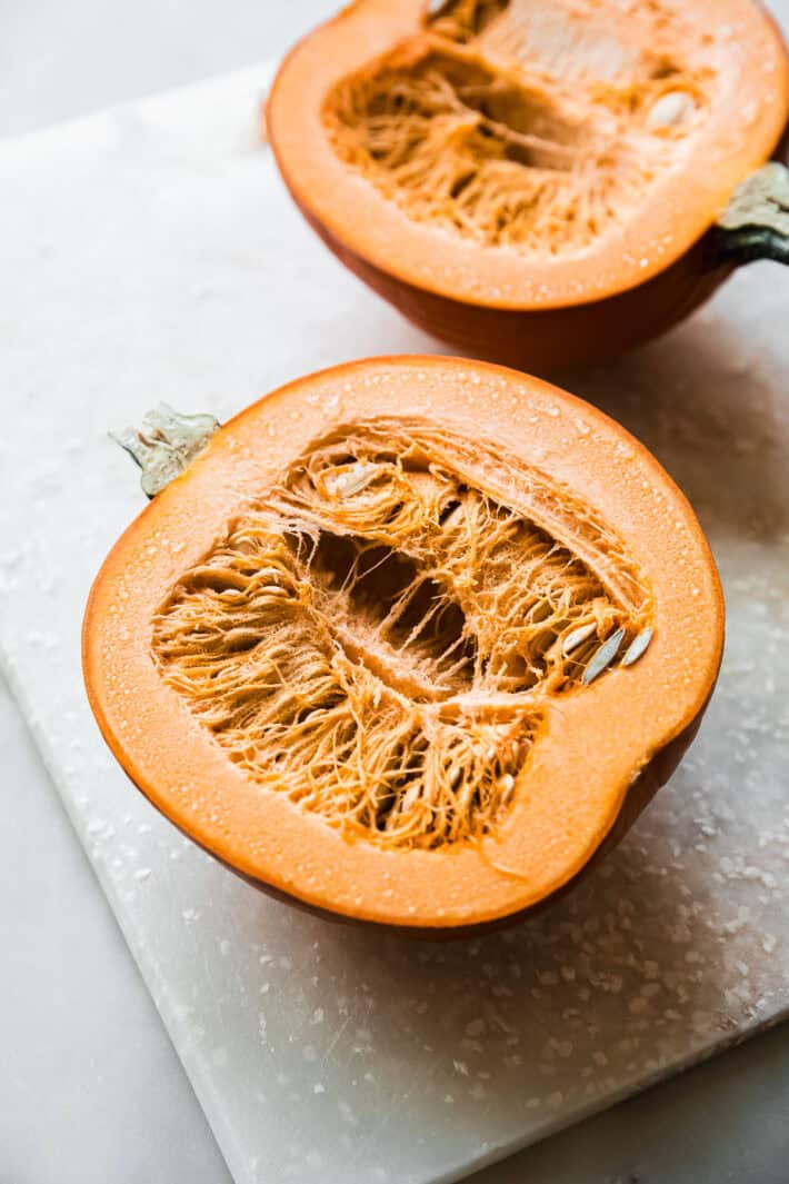 pumpkin halves on cutting board before cleaning