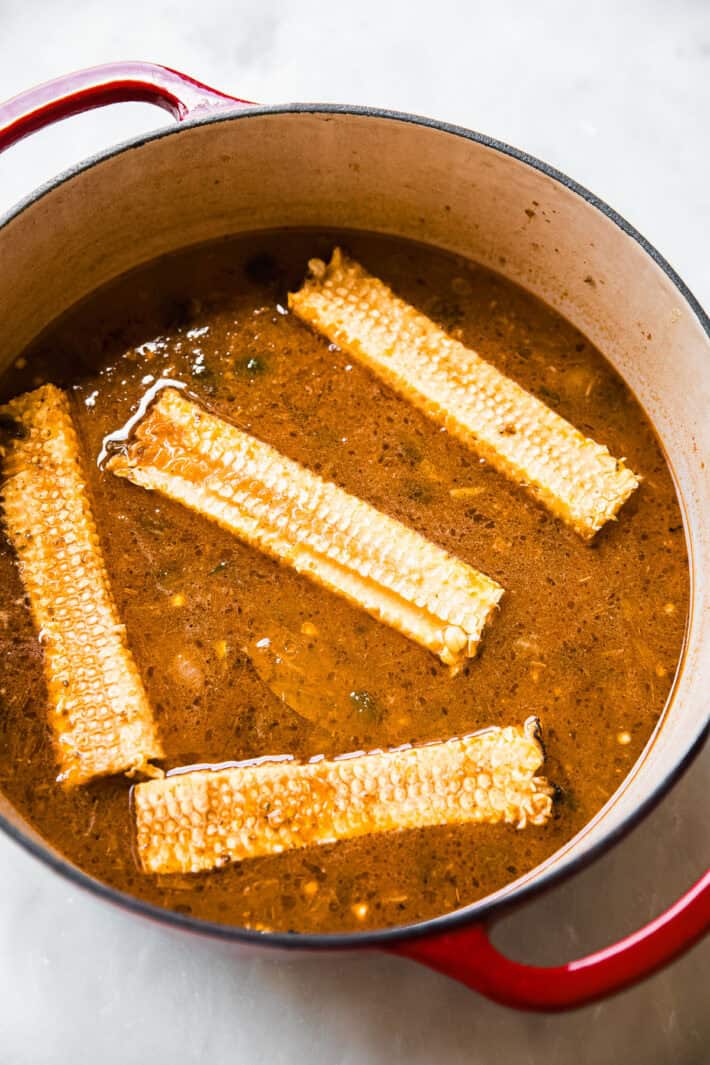 chicken and corn chowder in pot with cobs showing